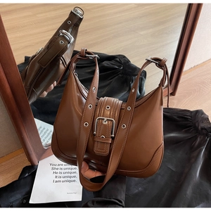 Dettaglio borsa a mezzaluna marrone con occhielli argentati e pelle liscia
