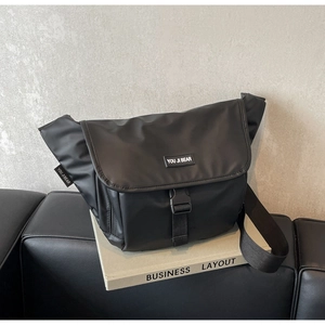 Detail of minimalist black nylon messenger bag with buckle closure and wide strap