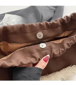 Detail of magnetic metal clasp and inner zipper pocket on brown leather bag