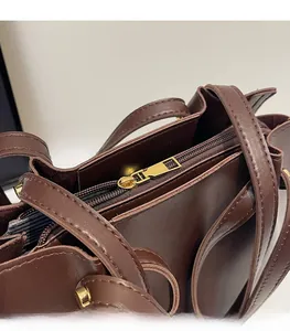 Detail of smooth gold zipper closure and premium brown leather texture on tote bag