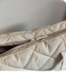 Detail view of smooth zipper and beige quilted fabric on high-capacity tote bag