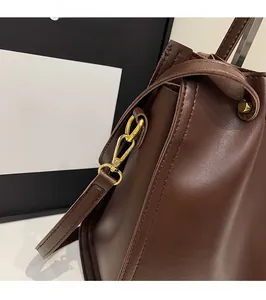 Detail view of deep brown matte leather tote bag with elegant gold metal hook and drawstring