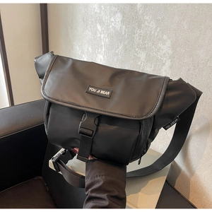 Detail of black messenger bag featuring heavy-duty buckle and adjustable shoulder strap