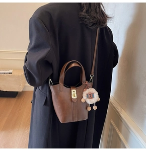 Detail of dark brown leather bucket bag with gold lock and cute sheep pendant charm