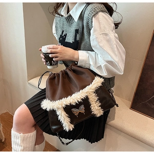 Close-up of brown PU drawstring bag with plush white trim and metal butterfly detail