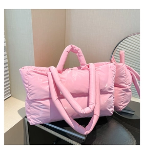 Detail of a pink glossy quilted tote bag with double handles and long shoulder strap
