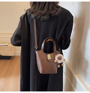 Detail of dark brown leather bucket bag with gold lock and fluffy sheep pendant