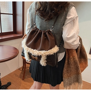 Detail of vintage brown drawstring backpack with plush trim and golden bow buckle