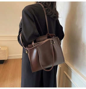 Detail of dark brown tote bag on model showing large capacity and smooth faux leather texture