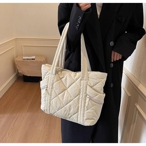 Detailed close-up of ivory quilted tote bag featuring functional side zipper pockets