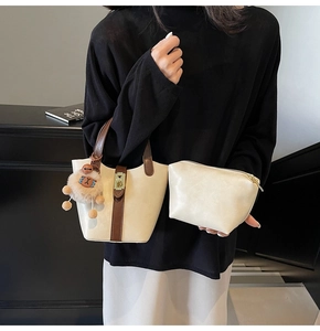 Detail of cream bucket bag and small pouch with contrast straps and lion plush charm