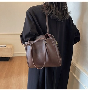 Detail of dark brown leather tote bag with slim straps and metallic rings in macro view