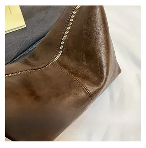 Close-up of brown lychee grain leather handbag featuring gold zipper and neat stitching