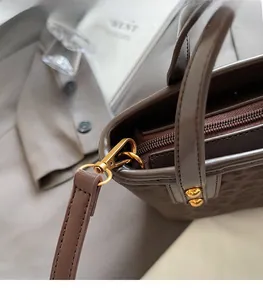 Detailed macro view of golden metal buckles and zipper on dark brown embossed leather handbag