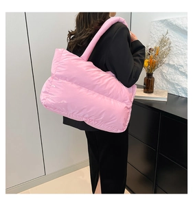 Detailed view of large pink quilted puffer tote bag on shoulder for fashion style