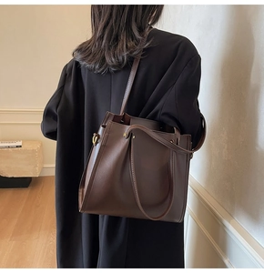 Detail view of deep brown leather tote bag with elegant gold hardware and shoulder strap