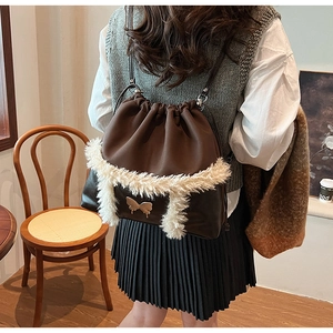 Detail of dark brown drawstring backpack with white faux fur trim and gold butterfly buckle