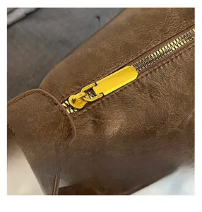 Close-up of vintage brown leather bag detail with gold metal zipper and textured finish