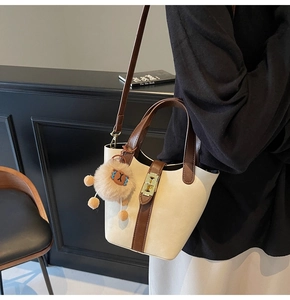 Detail of cream bucket bag with brown leather trim and a cute lion plush pendant charm