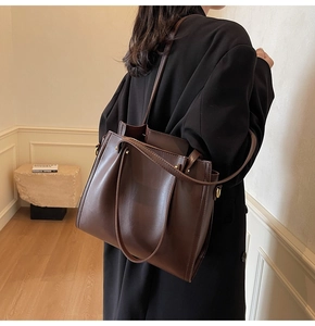 Detail view of dark coffee tote bag with gold hardware and fine leather texture