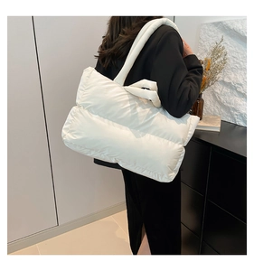 Detail of white quilted puffer tote bag showing soft texture and padded shoulder strap