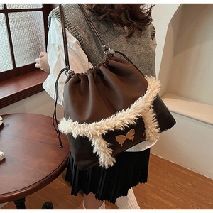 Close-up of deep brown leather bucket bag with fleece trim and gold butterfly clasp