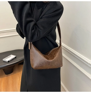 Model wearing a vintage dark brown crescent moon shoulder bag with thick strap