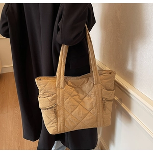 Close-up of khaki quilted tote bag with side zippers and wide shoulder strap