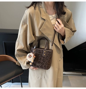 Detailed view of leopard print bucket bag with plush sheep charm and crossbody strap