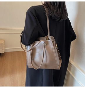 Brown leather tote bag featuring long shoulder straps and gold hardware on model