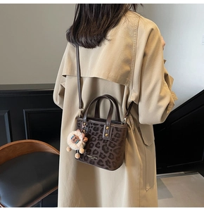 Close-up of a leopard print bucket bag styled with a beige trench coat on a model