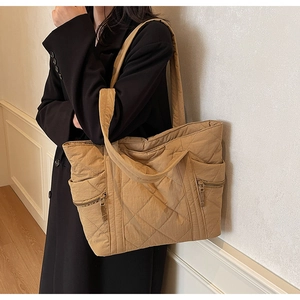 Detailed macro view of khaki quilted tote bag showing rhombus stitching and side zipper pocket