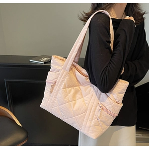 Detailed close-up of pink quilted tote bag with side zipper and diamond pattern texture