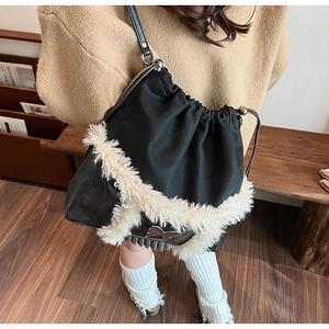 Detail of black drawstring bucket bag with white faux fur trim and silver bow charm