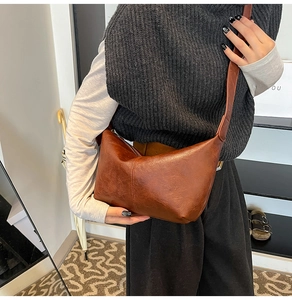Detail of vintage brown leather crescent bag worn as a crossbody with a minimalist finish