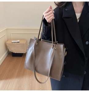 Detailed view of the brown leather tote bag with long straps and gold metal side buckles