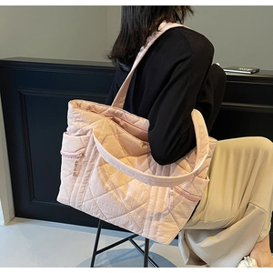 Detail view of pink quilted tote bag showing side zipper pocket and nylon material texture