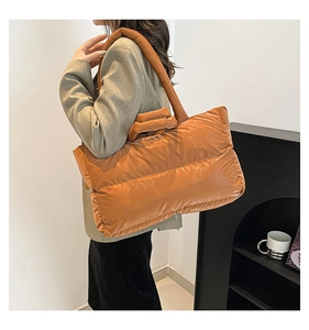 Detail of caramel brown quilted tote bag with glossy finish and thick padded handles