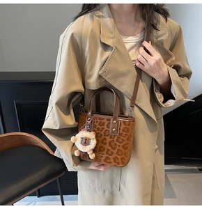 Detail of leopard print bucket bag with sheep charm and adjustable brown leather strap