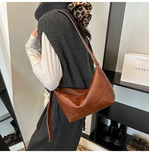 Side view of a vintage caramel brown soft leather tote bag worn by a model in a shop