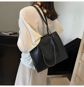 Close-up of a large black leather tote bag with elegant side stitching on the shoulder