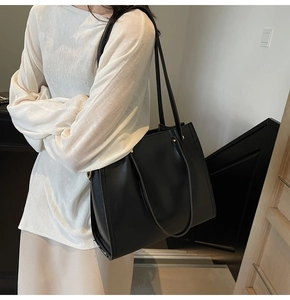 Detailed view of the black tote bag texture and high-quality shoulder strap with gold buckles