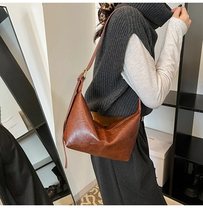 Close-up of retro brown leather hobo bag with adjustable strap and golden hardware