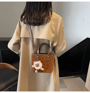 Detail of leopard print bucket bag with brown leather handles and alpaca charm