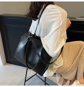 Model wearing a large black textured tote bag showcasing its size and commuter style on shoulder