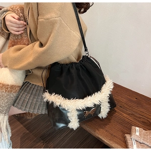 Close-up of black bucket bag featuring plush white faux fur trim and vintage metal butterfly
