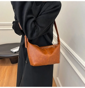 Close-up of caramel crescent bag with pebbled leather texture and gold zipper details