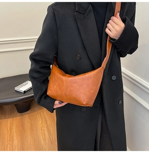 Brown vintage faux leather crescent bag styled on a model wearing a black coat