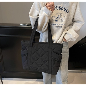 Detailed close-up of black quilted tote bag featuring classic diamond stitching pattern