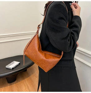 Detail of vintage brown oil wax leather handbag showing fine texture and metallic buckle
